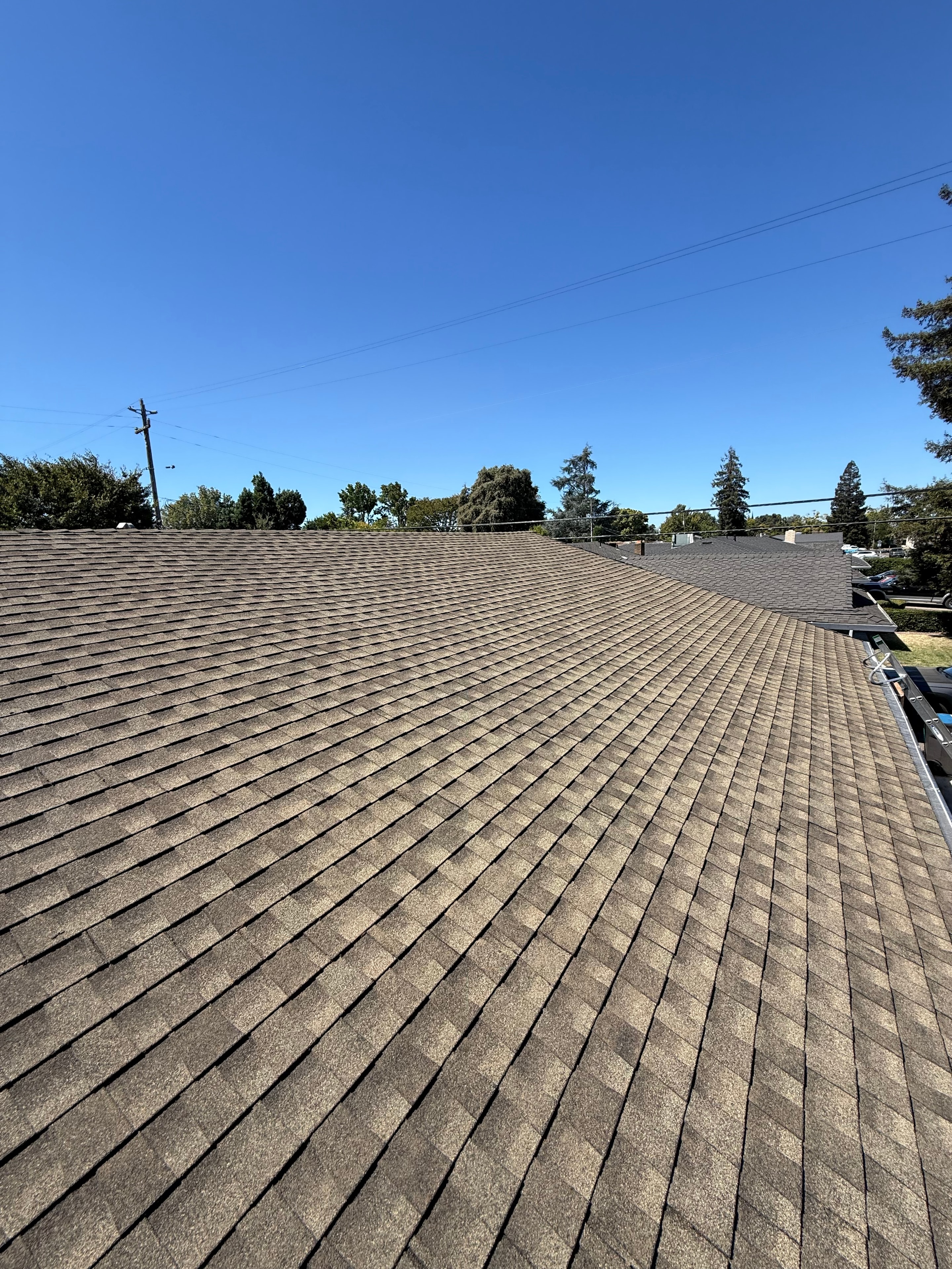 Residential shingle roof under a clear blue sky